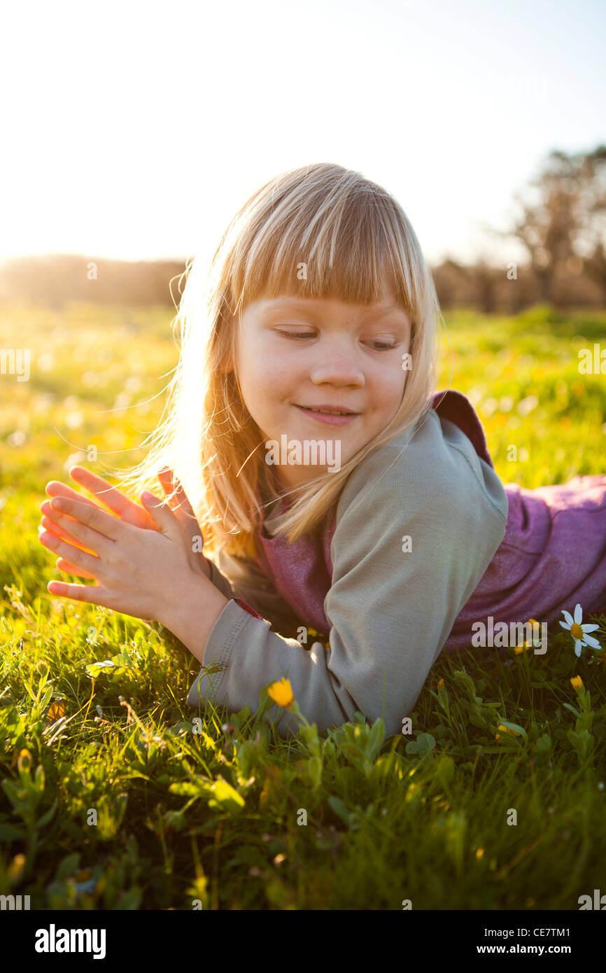 Cute little girl outdoors on a green field with flowers Stock Photo - Alamy