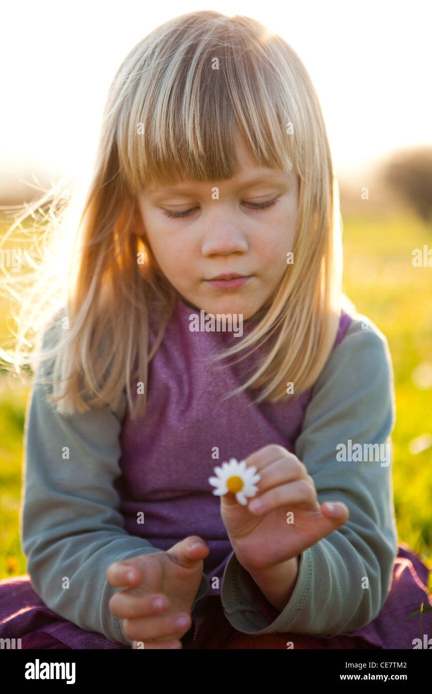 Cute little girl outdoors on a green field with a flower Stock Photo ...