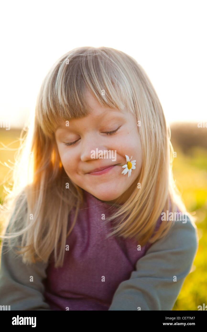 Cute little girl outdoors on a green field with a flower Stock Photo ...