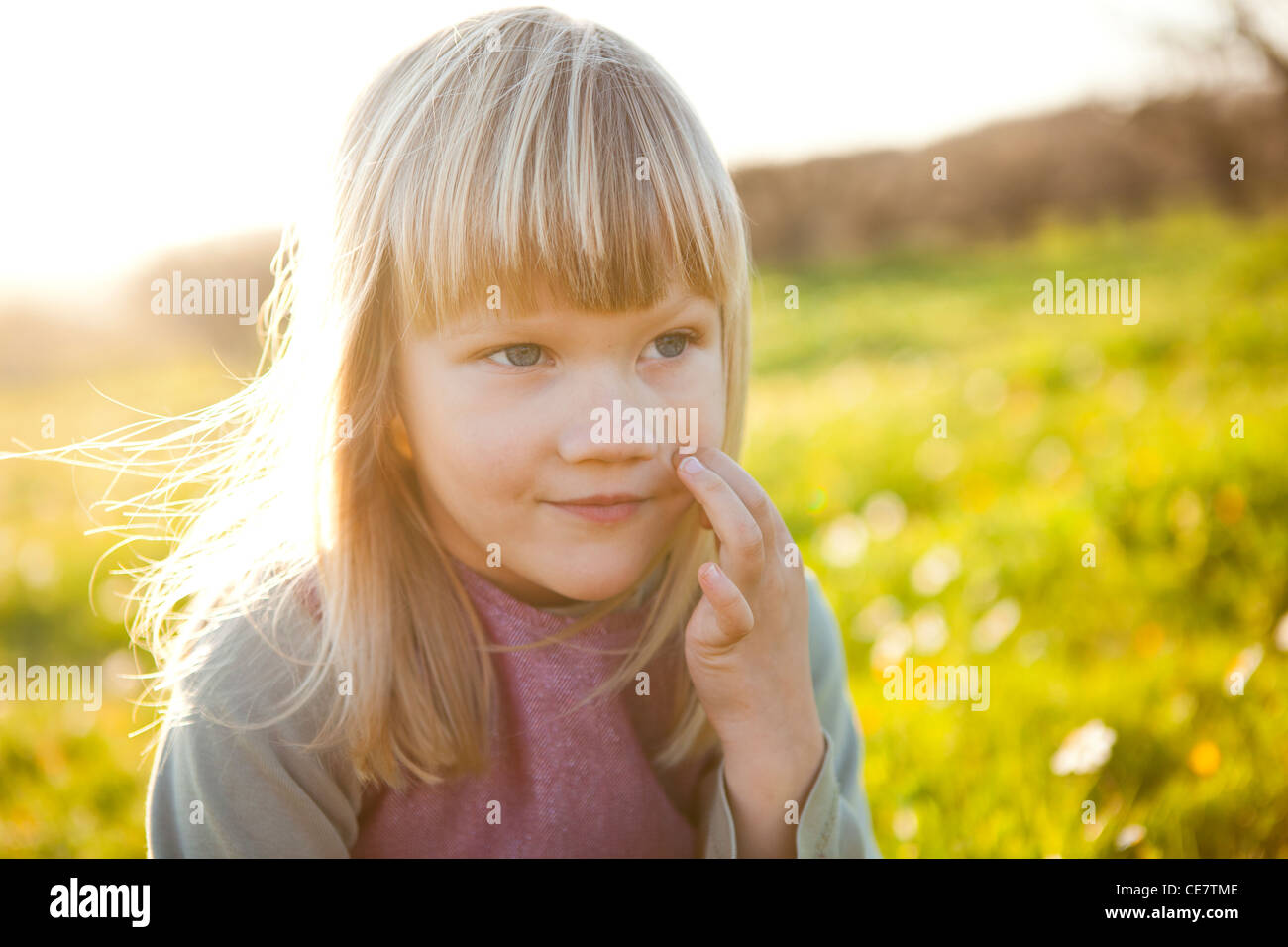 Cute little girl outdoors on a green field with flowers Stock Photo - Alamy