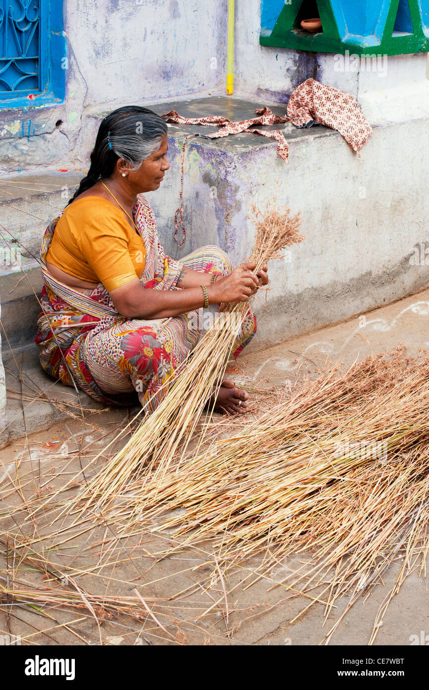 Indian woman making sweeping brushes out of dry grass stems. Andhra