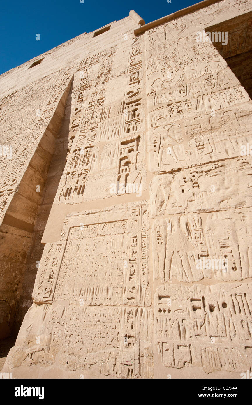 Egyptian hieroglyphic carvings and paintings on wall of the ancient temple at Medinat Habu in Luxor Stock Photo