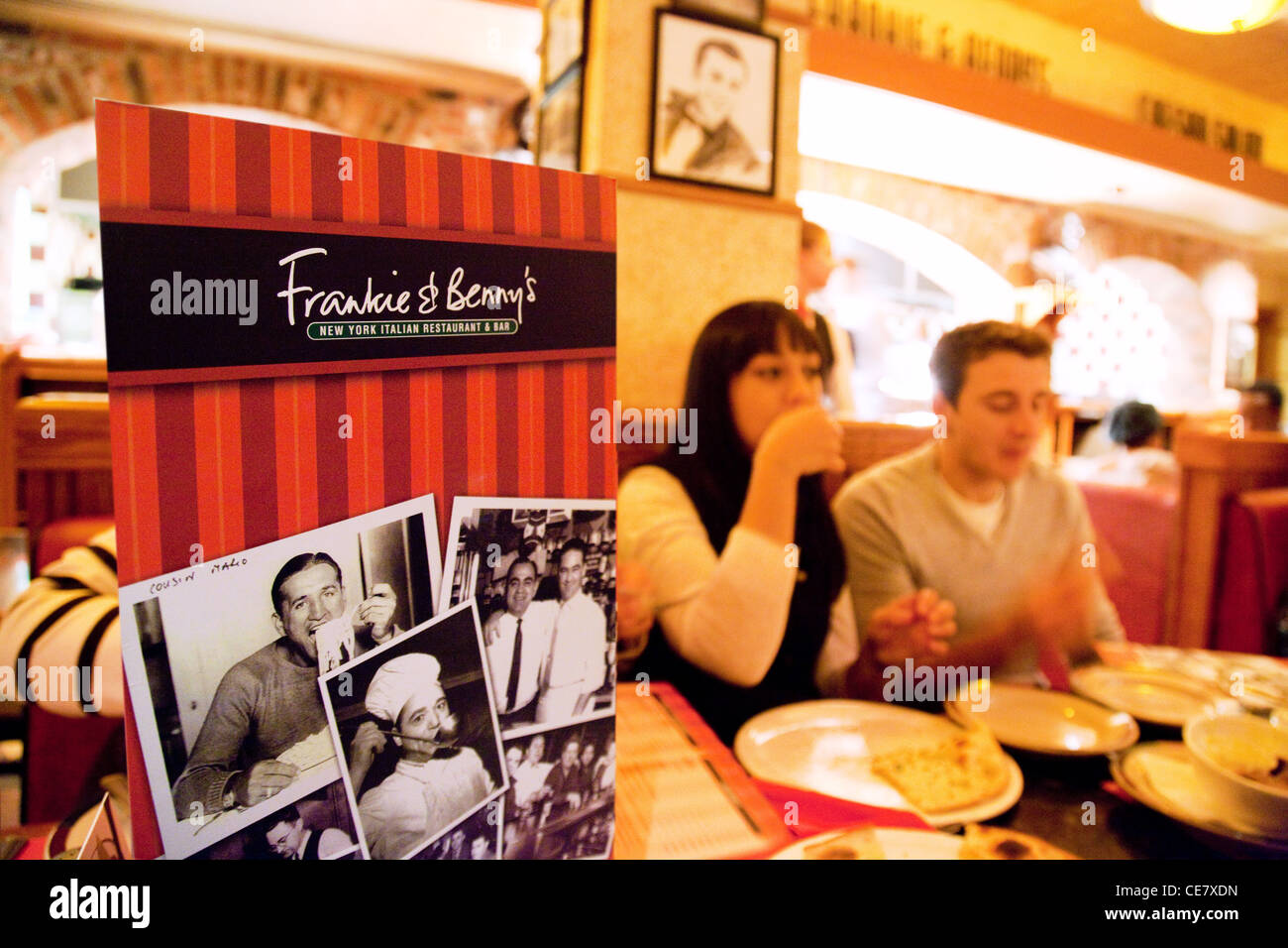 Menu and young couple eating inside Frankie and Benny's restaurant bar, Cambridge UK Stock Photo