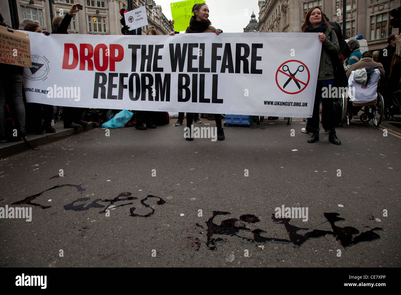 Cuts Kill is written in fake blood on the street. Disabled and able bodied demonstrators protest against the Welfare Reform Bill Stock Photo