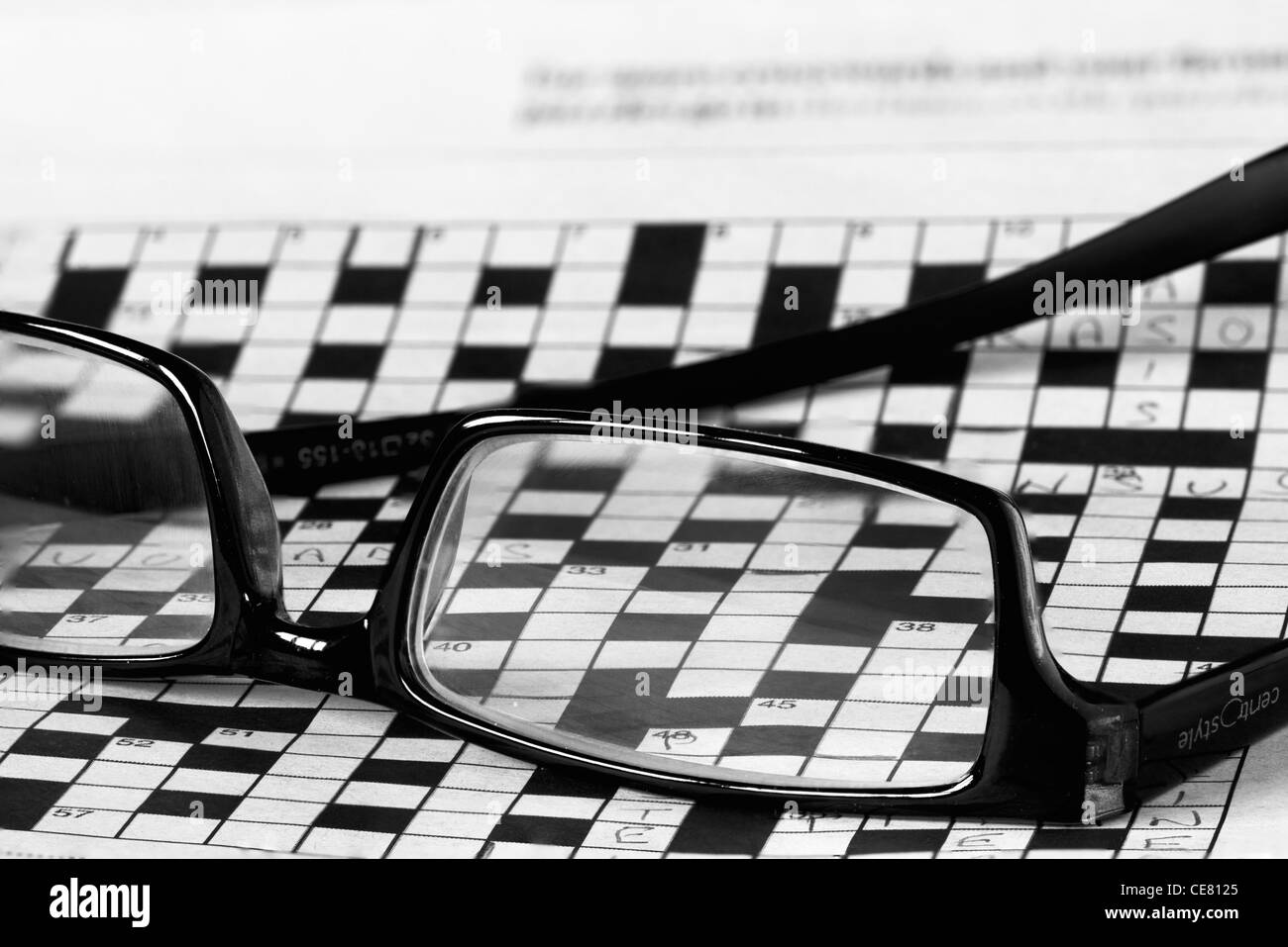 A pair of reading glasses lying upturned on top of a large incomplete crossword Stock Photo