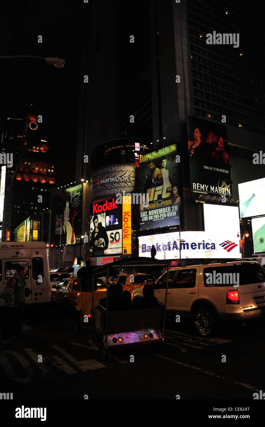 Night portrait traffic rickshaw pedicab overtaking white van, neon billboards, 7th Avenue at West 46th Street, New York Stock Photo