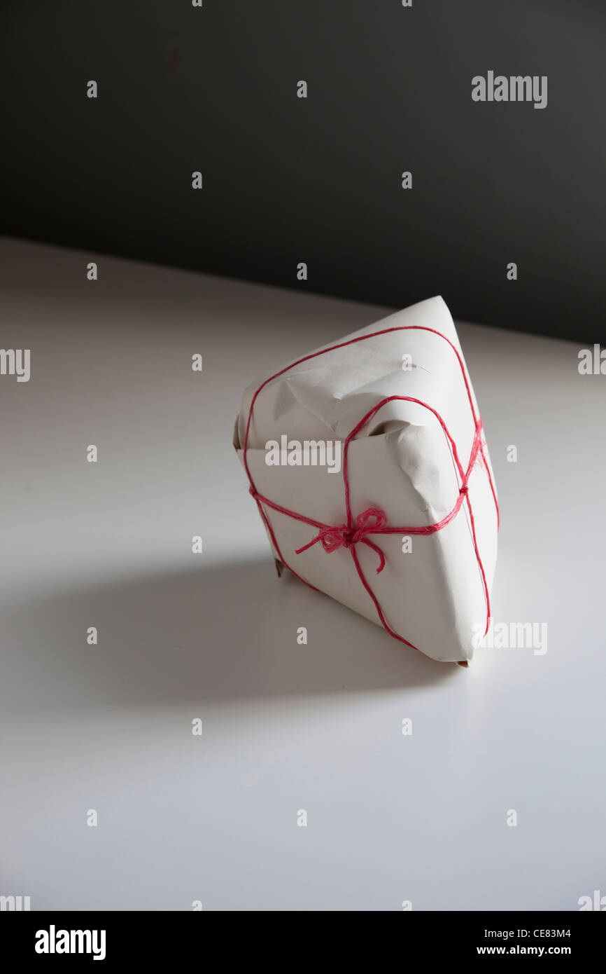Triangular Wrapped a plainly wrapped triangular package on a white table. the package ...