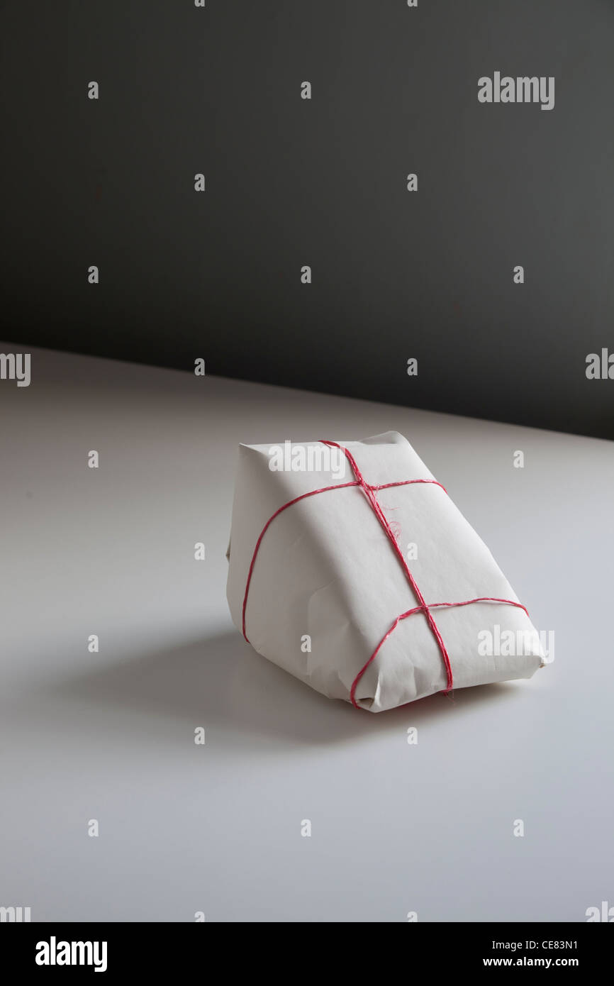 Triangular Wrapped a plainly wrapped triangular package on a white table. the package ...