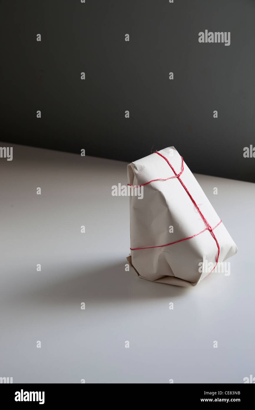 Triangular Wrapped a plainly wrapped triangular package on a white table. the package ...