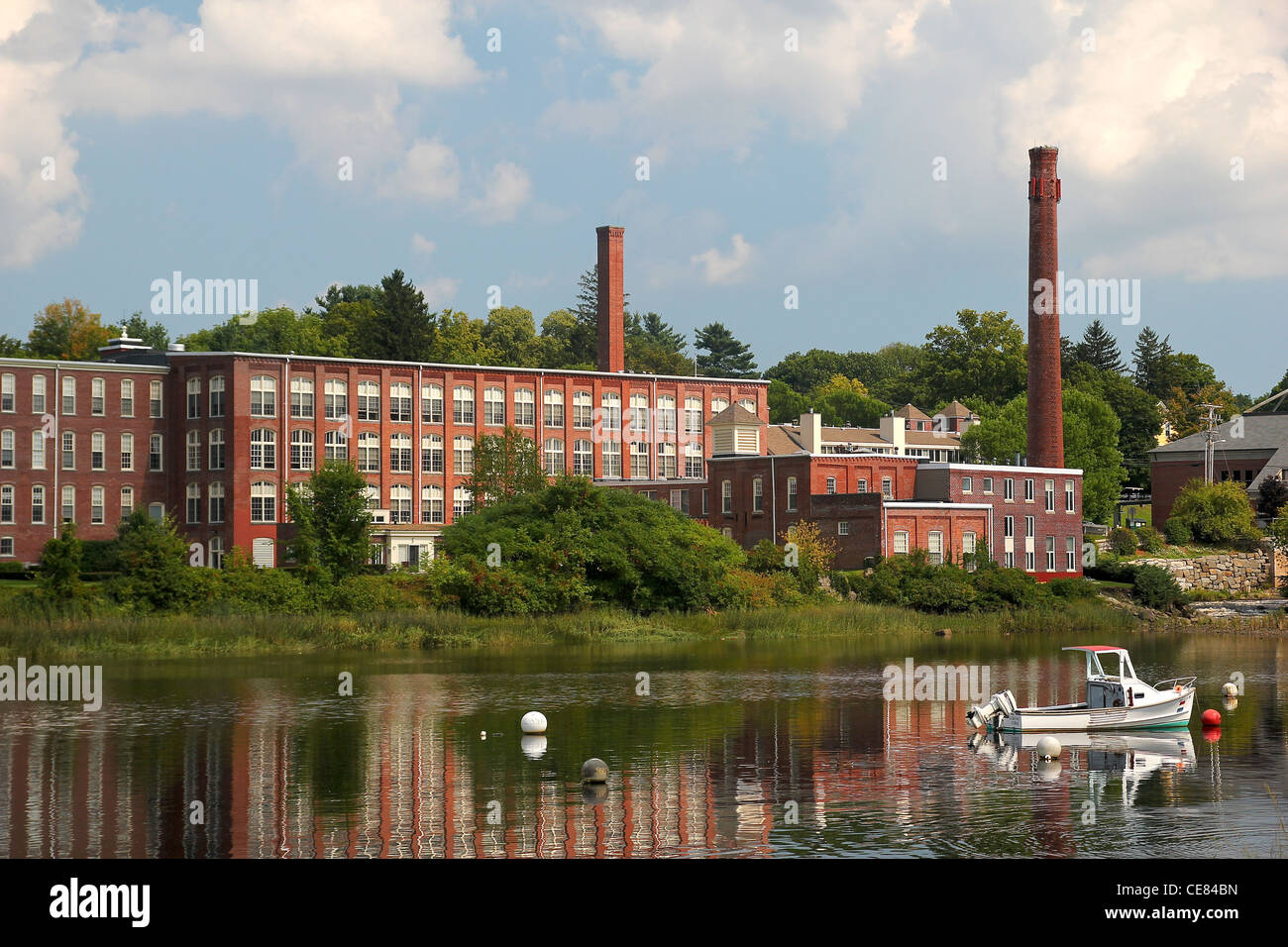 Old factory buildings and a boat on the water in Exeter, New Hampshire Stock Photo