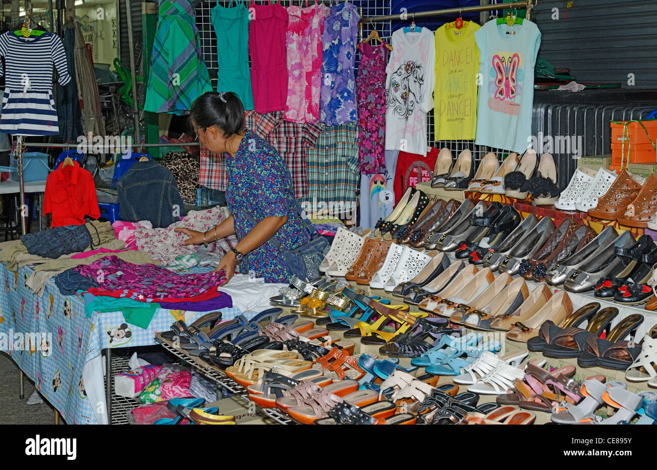 Market stall selling women's shoes and t-shirts in Bangkok. Stock Photo