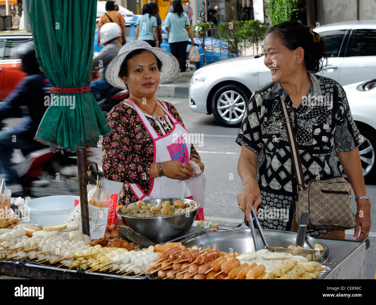 Two Thai ladies working on a hawker stall selling Thai and Asian foods in Silom area of Bangkok Stock Photo