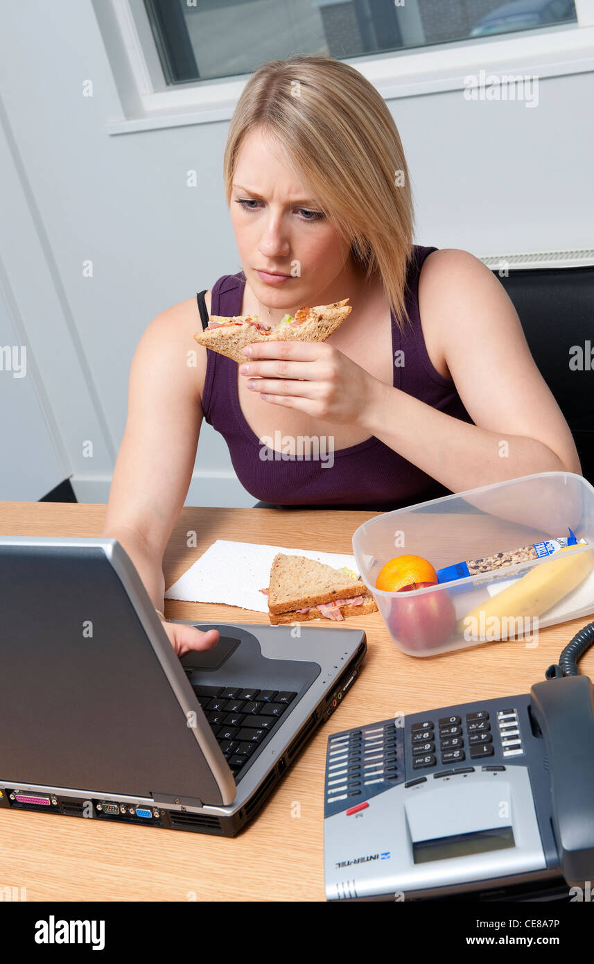 female office worker eating working lunch Stock Photo - Alamy