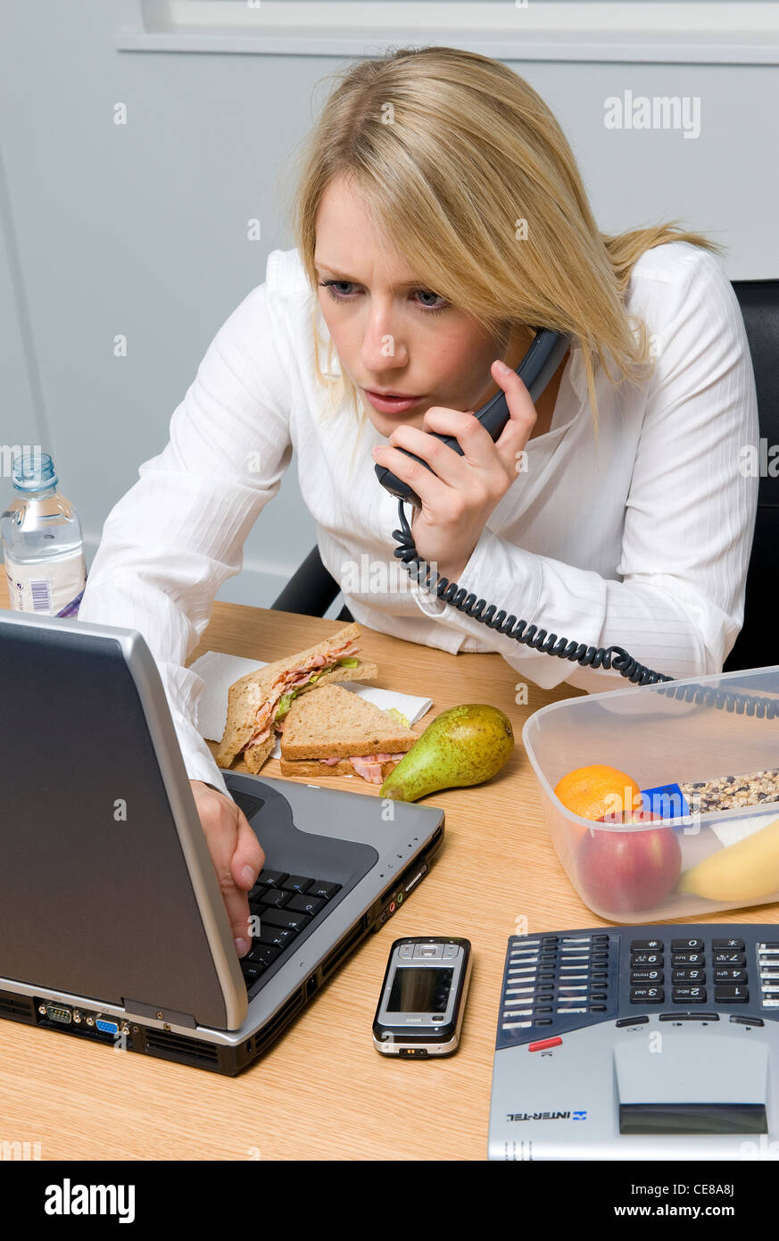female office worker eating working lunch Stock Photo