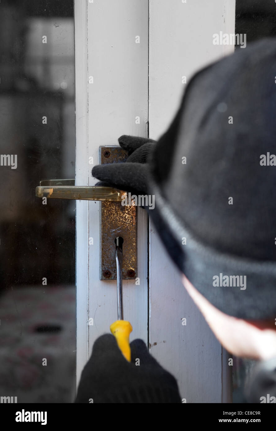 Breaking and entering home or house, Burglar with screwdriver force open door. Thief attempting to breach security Stock Photo