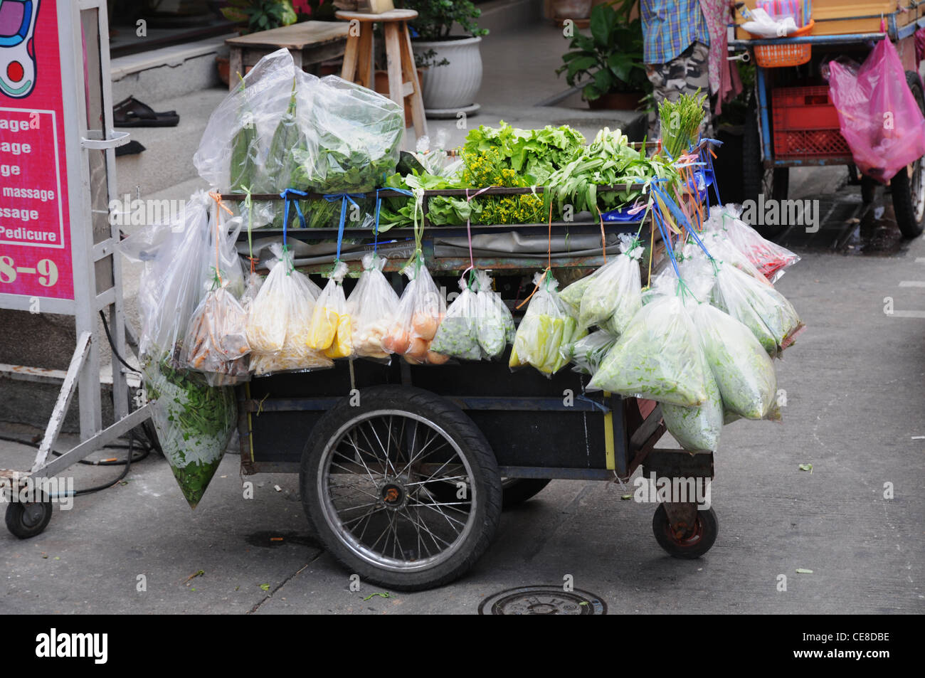 street vendor, trader, cart with vegetables and fruit in street market