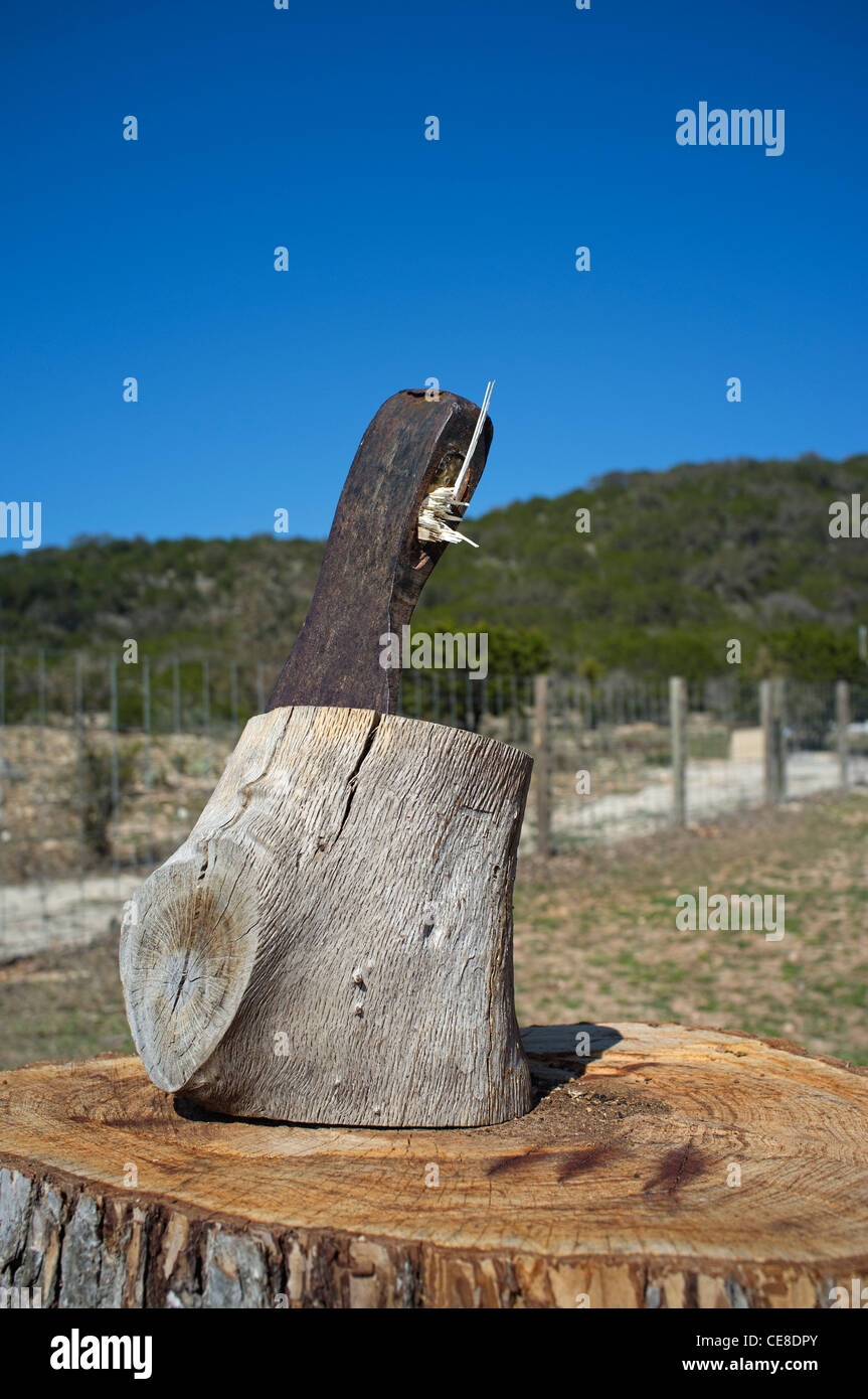 Ax with broken off handle is stuck in a piece of hard wood Stock Photo