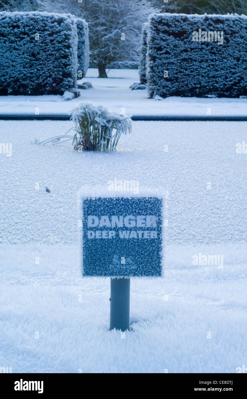 Large crystals of hoar frost on a Danger Deep Water sign by ice of a frozen pond, in the garden of Dunvegan Castle Stock Photo