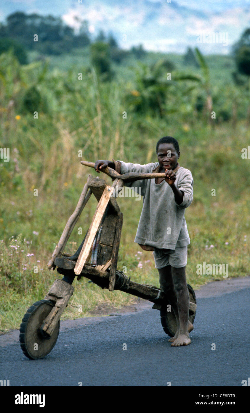 African boy in Zaire standing with a home-made wooden scooter Stock Photo