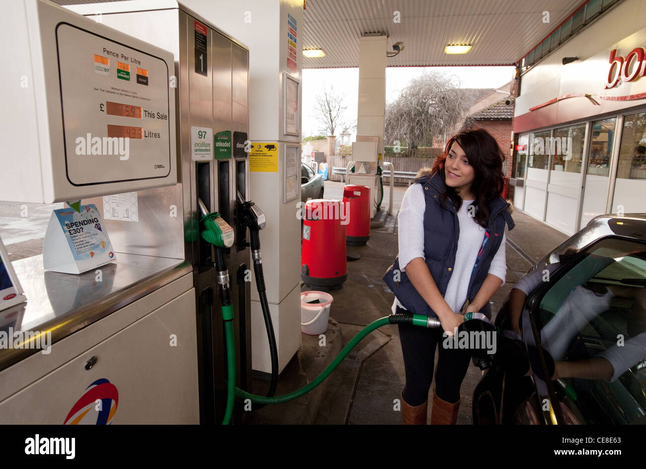 Teenage girl filling her car with unleaded petrol at a petrol station, UK Stock Photo