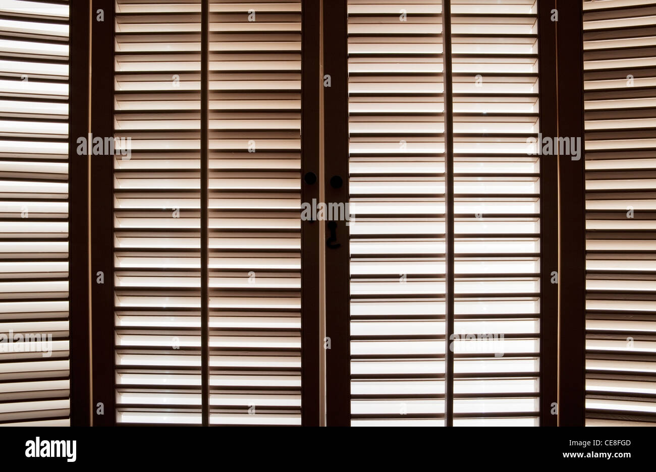 Wooden shutters in front of bright, sunlit windows Stock Photo
