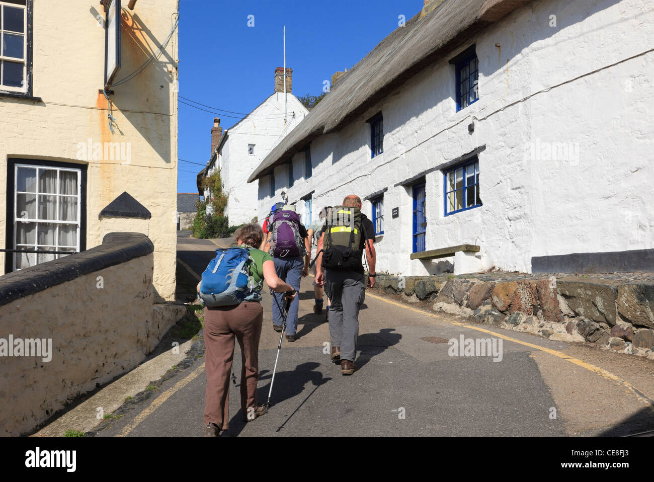 Group of walkers walking up steep hill through narrow village street