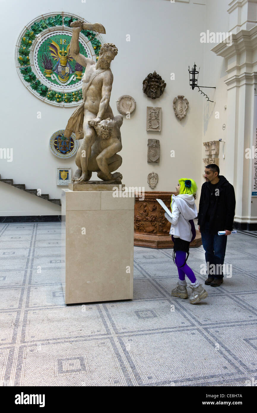 green haired and purple legged girl with companion in sculpture gallery, Victoria and Albert Museum, London, England, UK Stock Photo