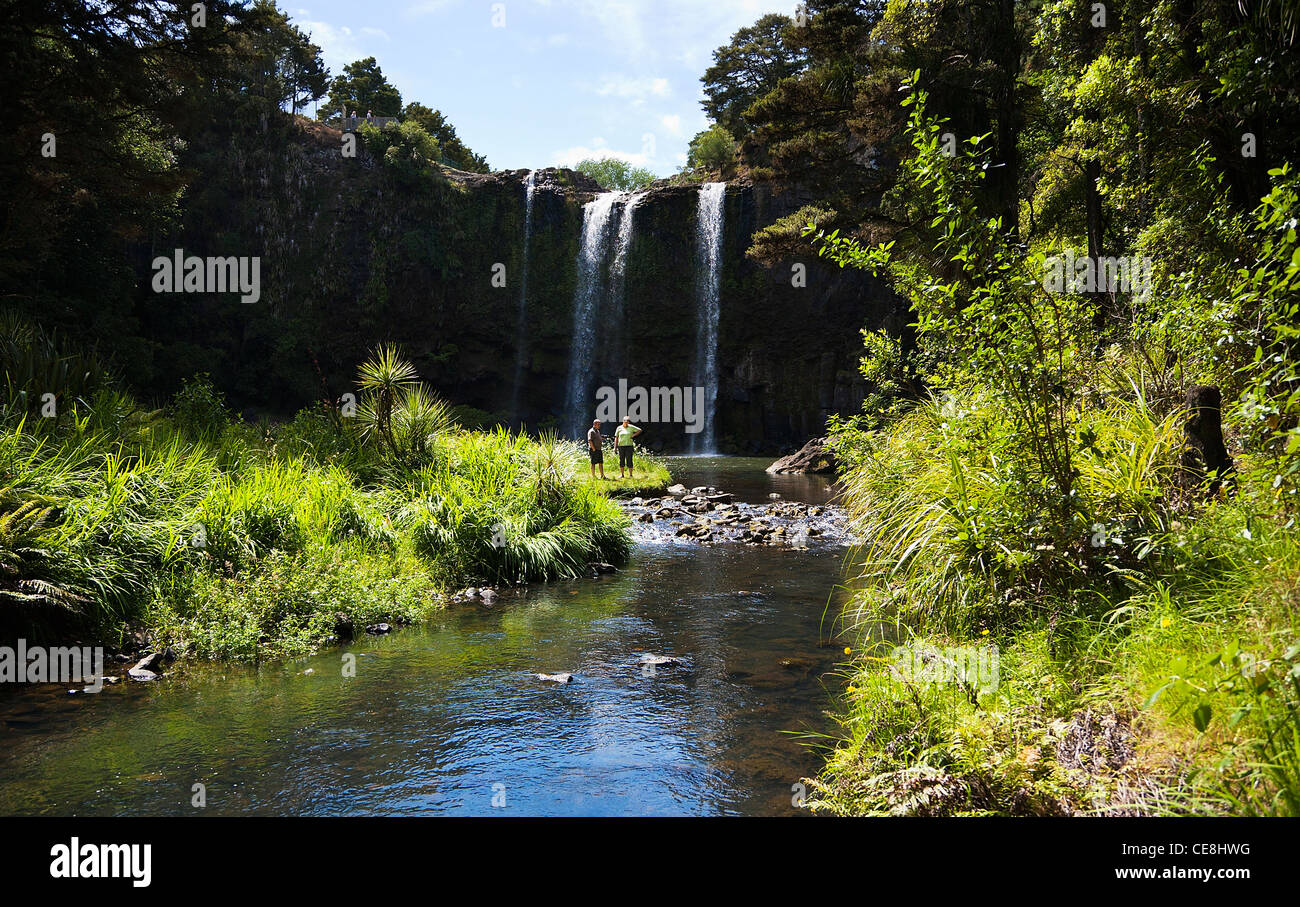A couple standing at the base of Whangarei Falls on the Hatea river, Northland, North Island, New Zealand. Stock Photo