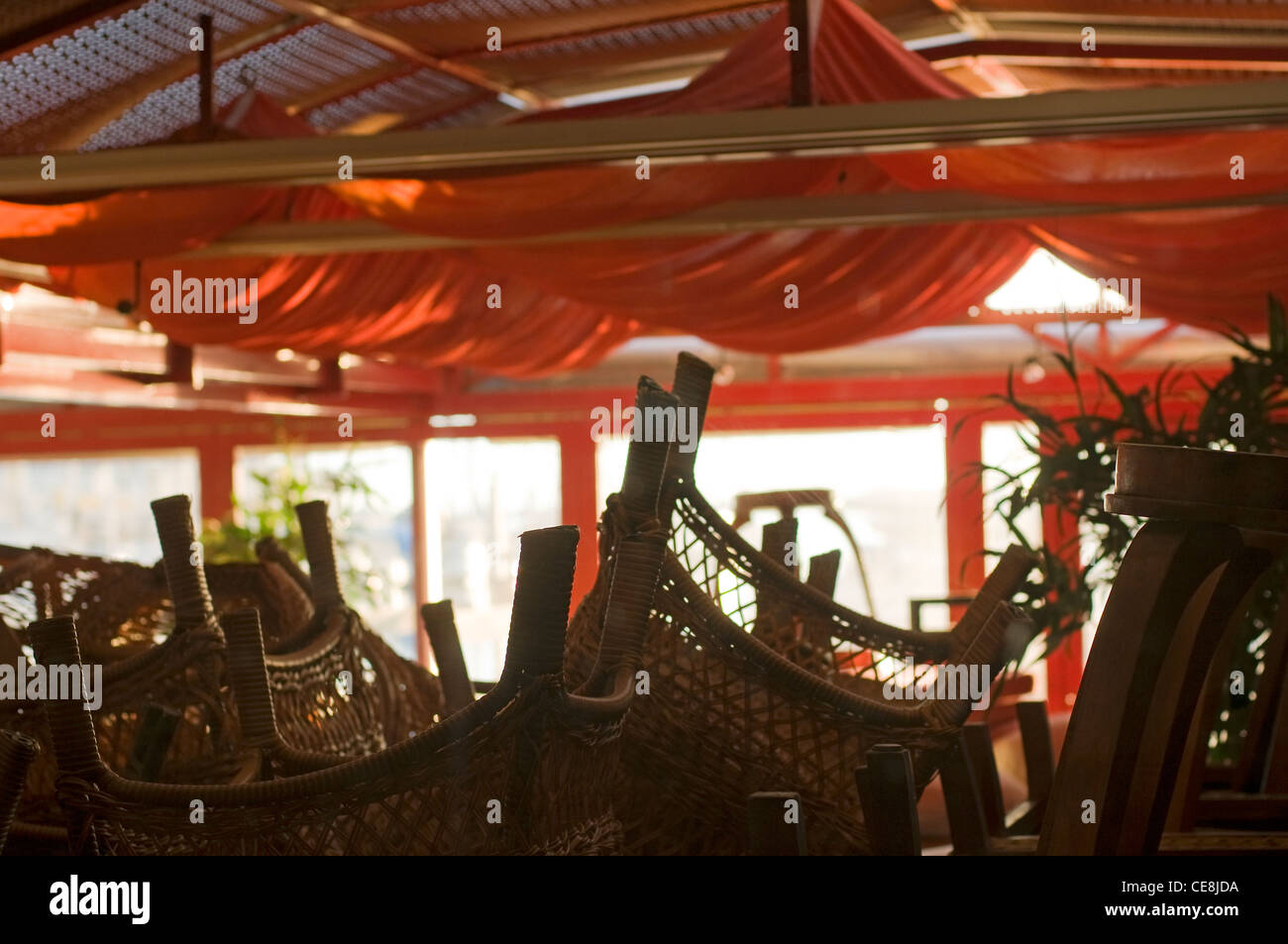 Upturned chairs on tables in restaurant during out of season period,in the popular Holiday resort of Cap D'Agde in France Stock Photo