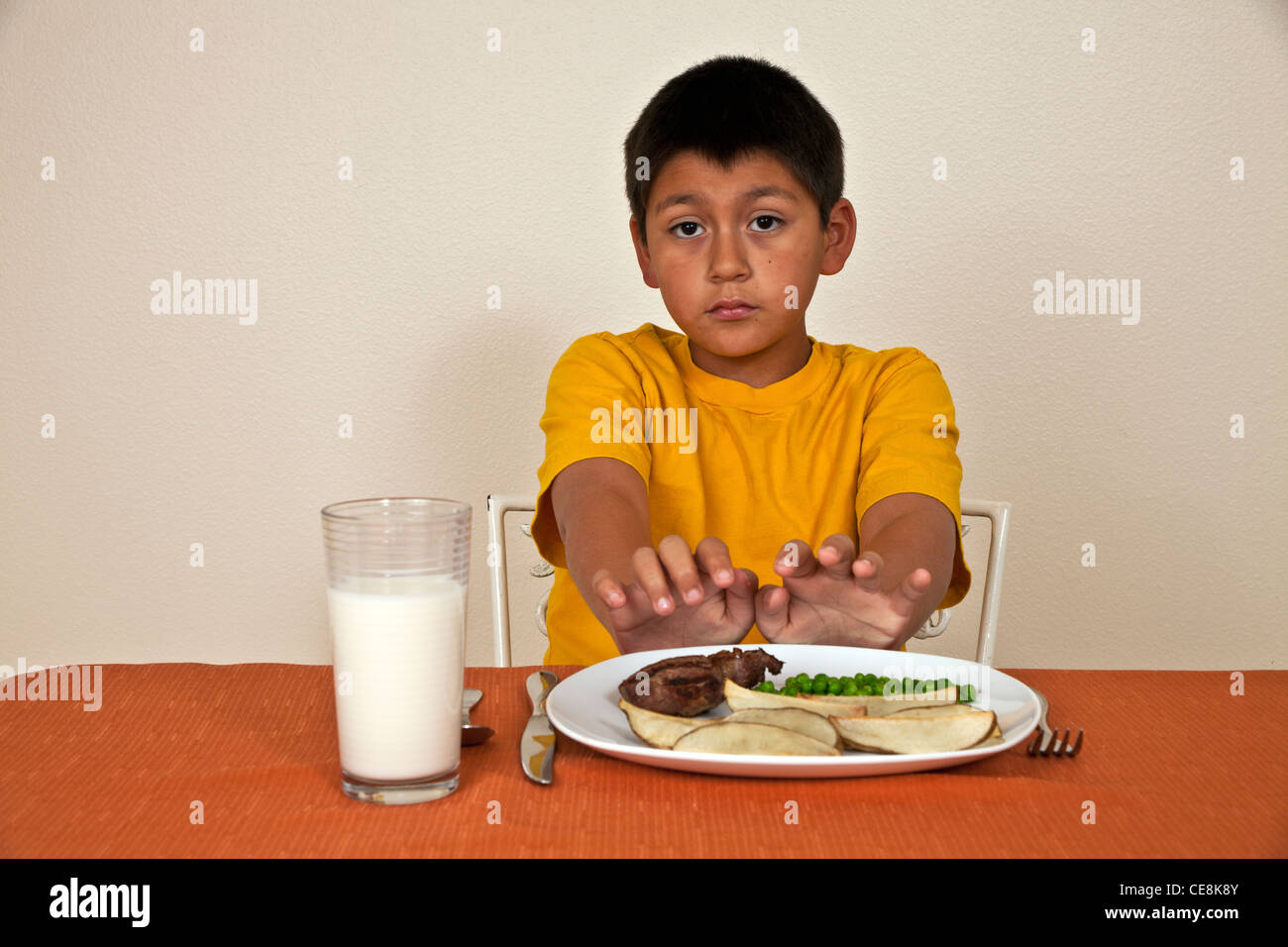 Strong willed stubborn 10-11 year old Hispanic boy doesn't want to eat  multi racial diversity racially diverse multicultural cultural. Stock Photo