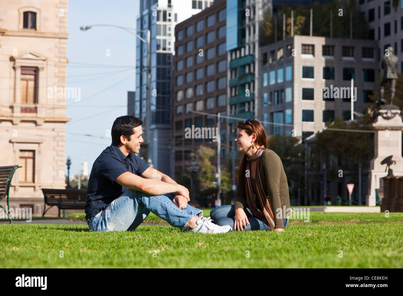 Young couple relaxing in park with city skyline in background. Gordon Reserve, Melbourne, Victoria, Australia Stock Photo