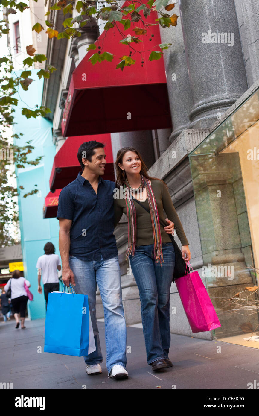 Couple with shopping bags looking in shop windows. Collins Street