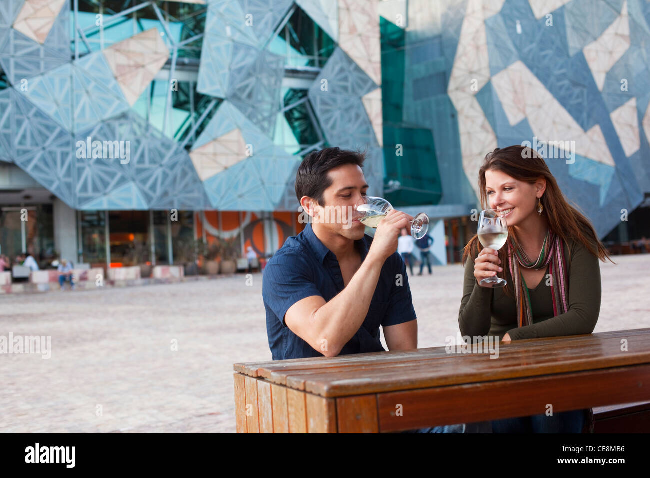 Young couple enjoying drink at an outdoor bar. Federation Square, Melbourne, Victoria, Australia Stock Photo