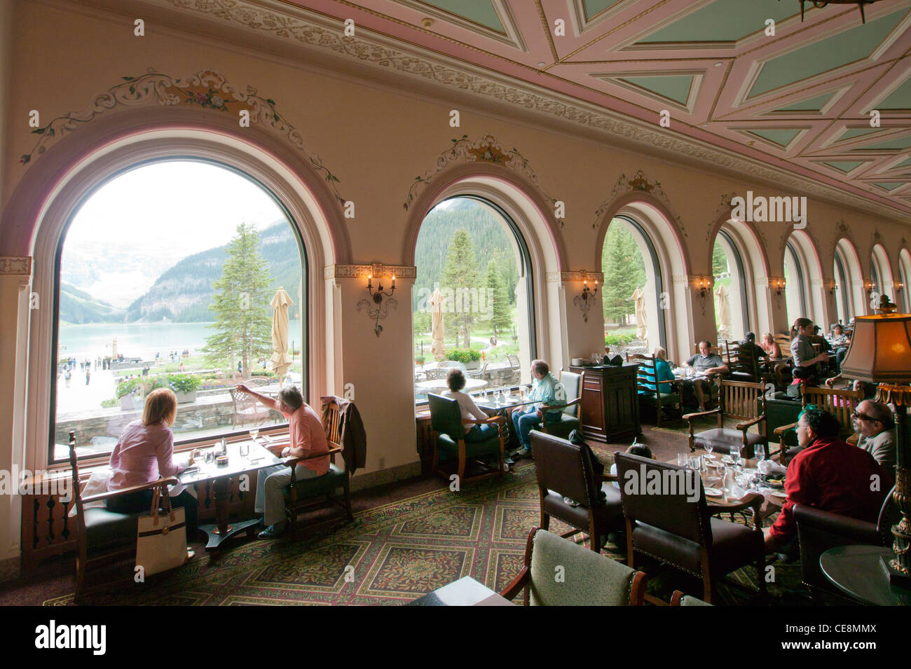 People viewing Lake Louise from the restaurant inside The Fairmont Chateau Lake Louise Hotel in Banff National Park Alberta Canada Stock Photo
