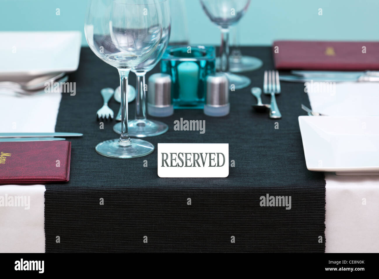 Photo of a Reserved sign on a restaurant table with menus on the side and place settings for two people. Stock Photo