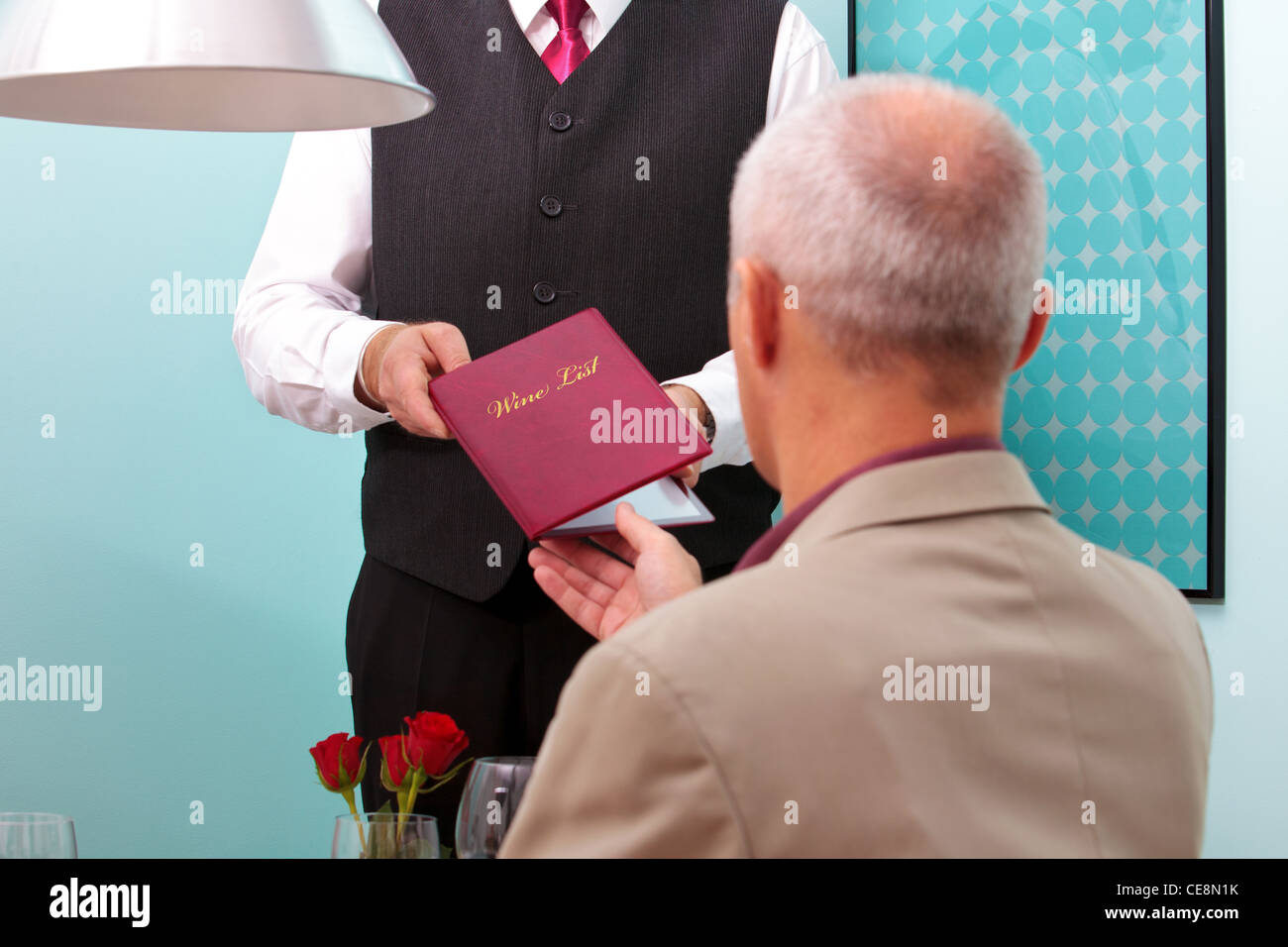 Photo of a sommelier handing a wine list to a restaurant customer. Stock Photo