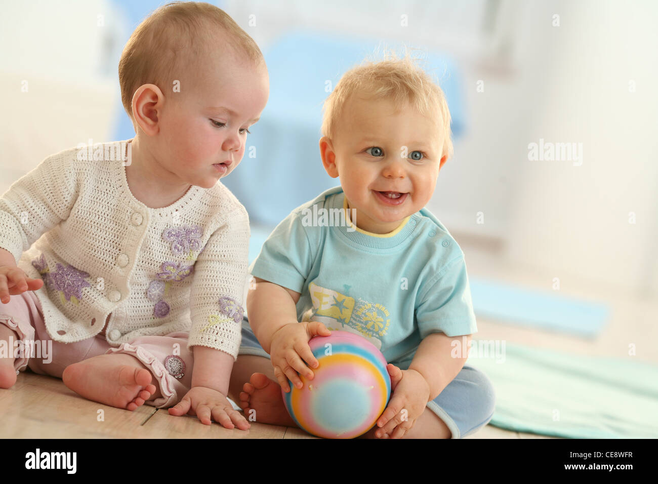 Two babies sitting on the floor Stock Photo Alamy