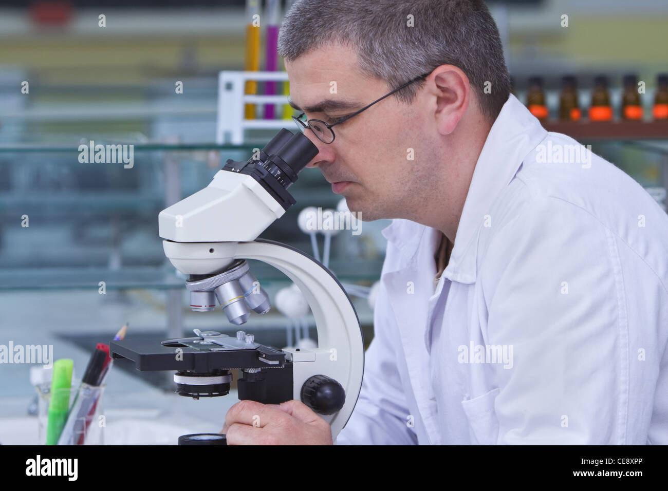 Male researcher looking through a microscope in a laboratory. Stock Photo