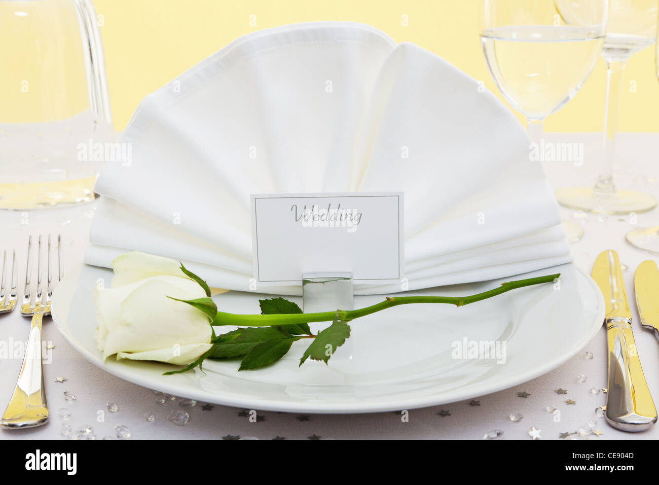 Photo of a table place setting for a wedding with a white rose on the plate. Stock Photo