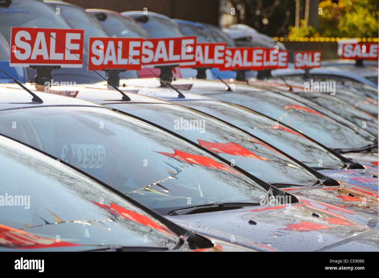 Car sale red signs above windscreen long line second hand pre owned motor cars to buy from Ford car dealership forecourt in Brentwood Essex England UK Stock Photo