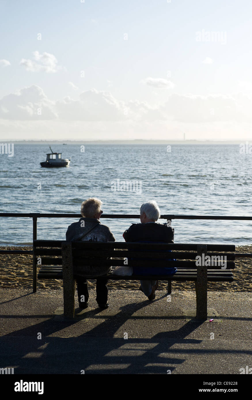 Two people sitting on a bench overlooking the Thames Estuary Stock Photo