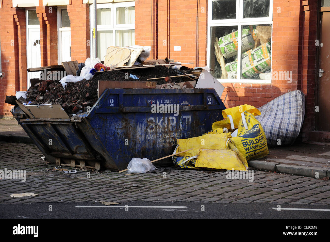 Blue builders skip full, outside house Stock Photo - Alamy