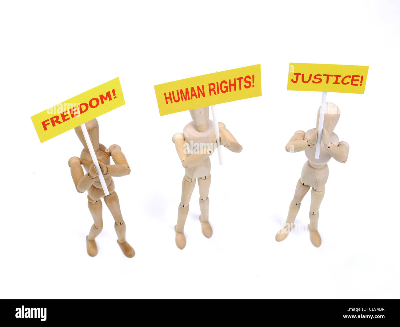 Three wooden dummies as demonstrators holding placards saying - Freedom, Human Rights and Justice shot on white background Stock Photo