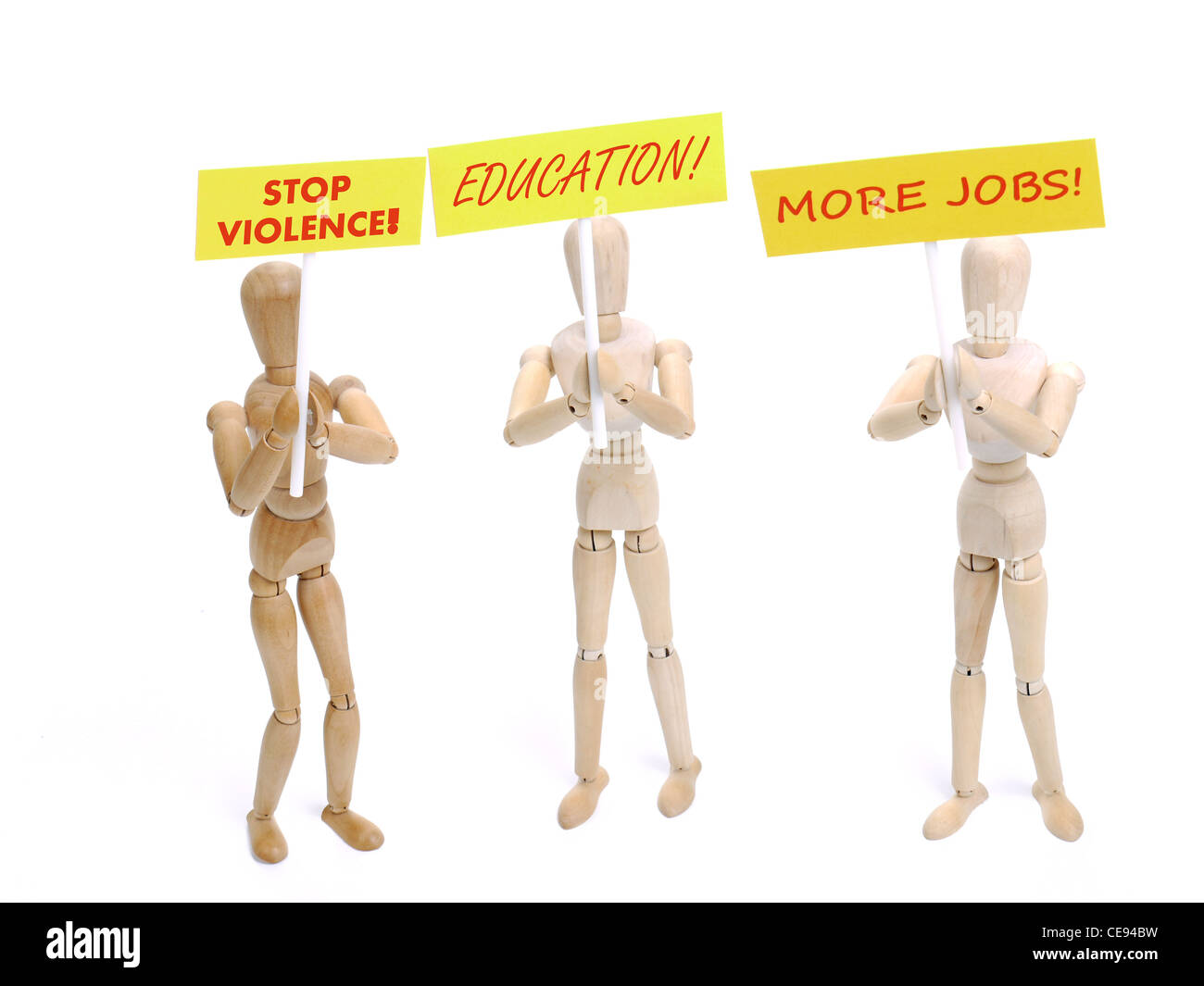 Three wooden dummy demonstrators holding placards saying - Stop Violence, Education and More Jobs shot on white background Stock Photo
