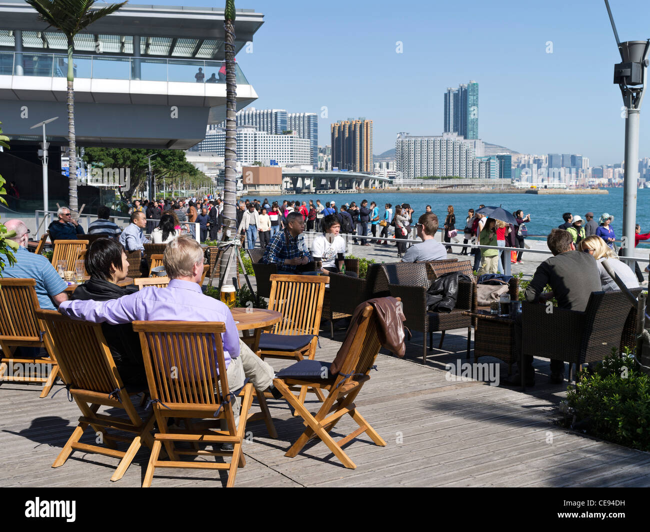 dh  TSIM SHA TSUI EAST HONG KONG People relaxing Starbucks kowloon cafe Victoria harbour waterfront promenade china couple in outdoor cafes Stock Photo