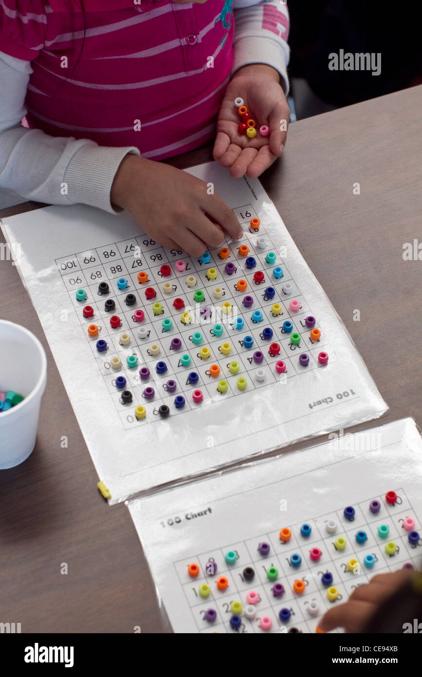 elementary age student  in classroom complete  a math counting exercise with colorful beads Stock Photo