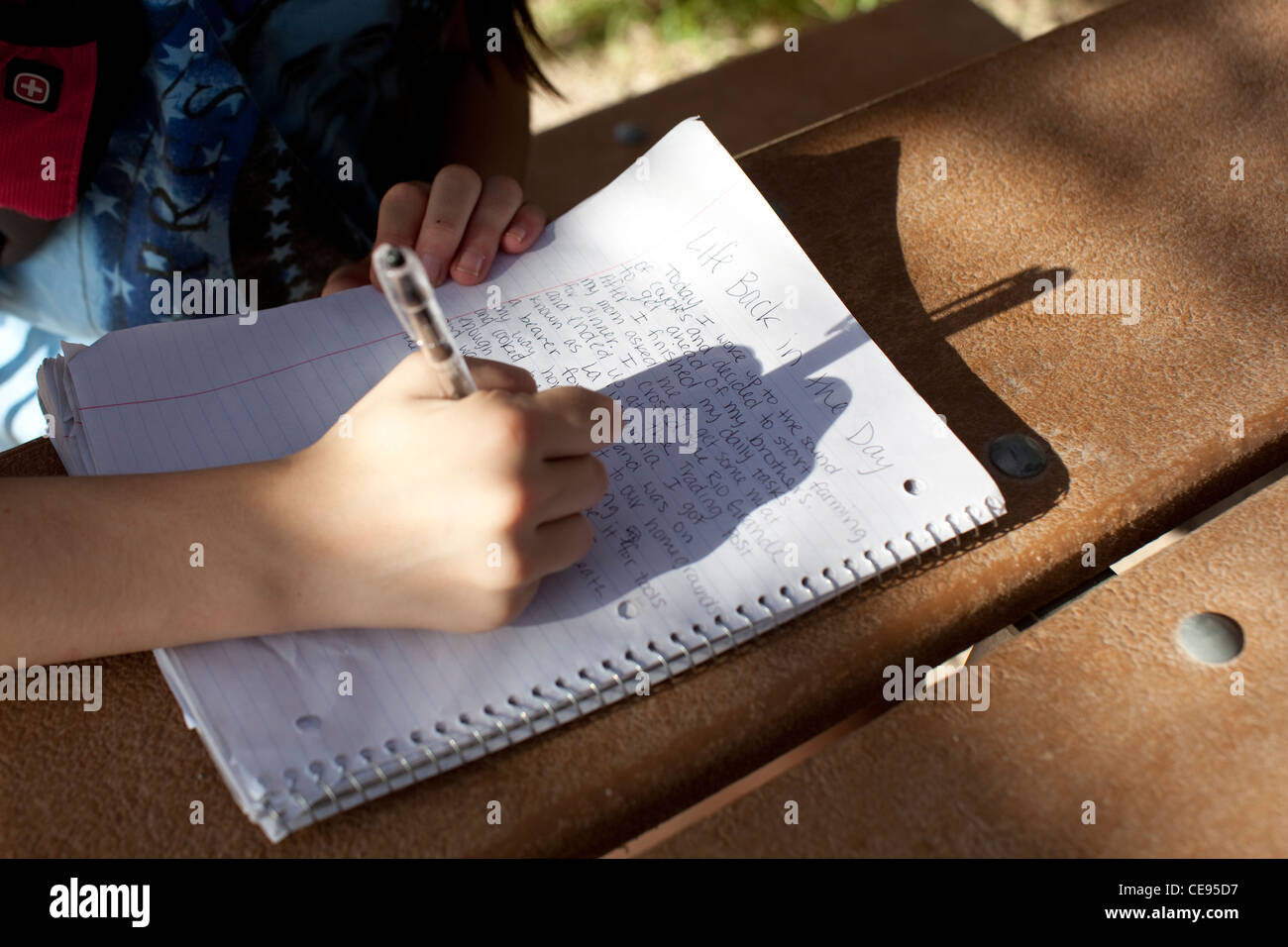 Teenage middle school female student hand writes report during school camping trip to Big Bend National Park in Texas Stock Photo