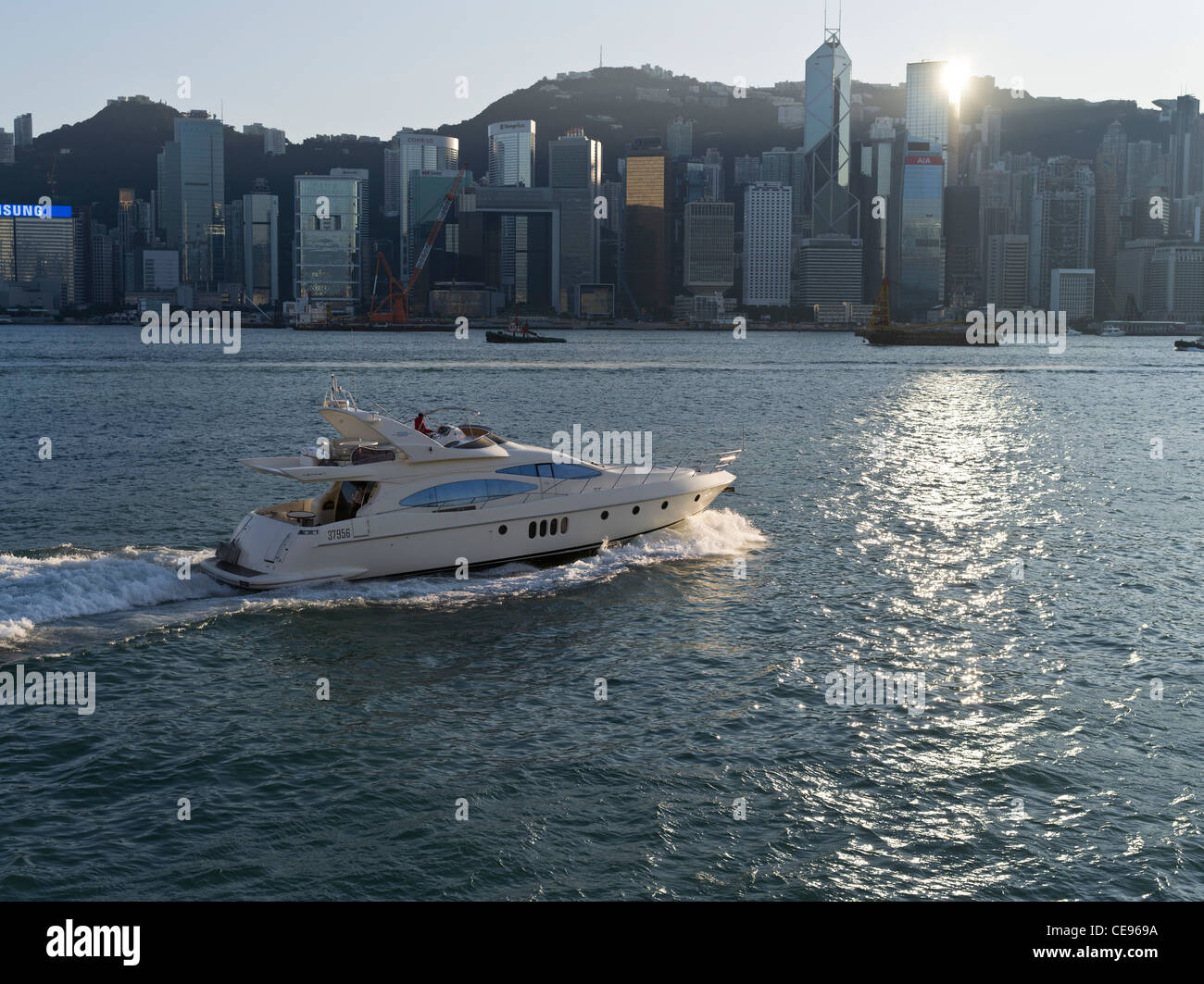 dh  HONG KONG HARBOUR HONG KONG Expensive modern motor cruiser Hong Kong island waterfront buildings boat Stock Photo