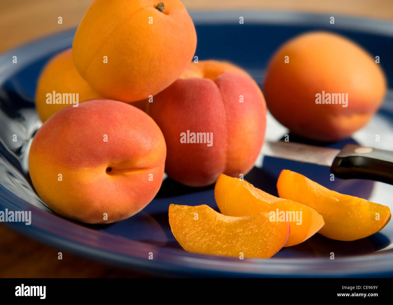 Whole and sliced apricots on a blue ceramic plate. Stock Photo