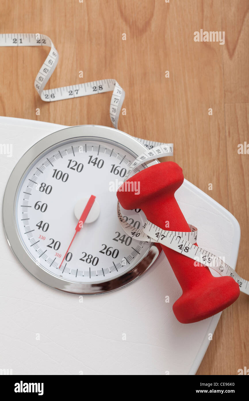 Dumbbell and tape measure on bathroom scales Stock Photo Alamy